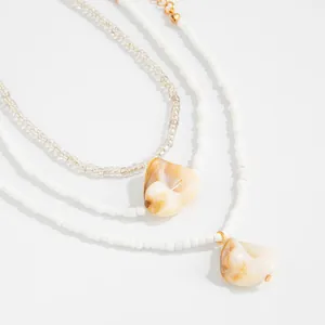 Close-up detail of Bohemian white seed bead anklets featuring marbled shell pendants