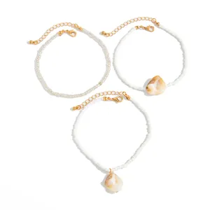 Macro detail view of Bohemian seed bead anklets featuring natural shell pendants and gold clasps.