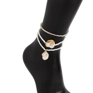 Close-up of bohemian white beaded anklets with natural shell pendants on a display