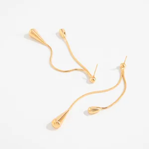 Detailaufnahme eleganter goldener Quastenohrringe mit minimalistischen Tropfenanhängern.