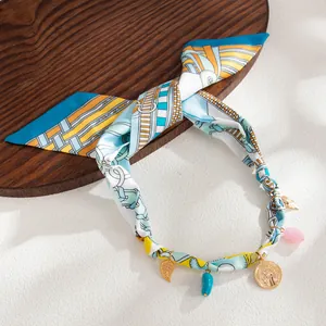 Detail of Bohemian printed silk scarf necklace with gold coin and resin leaf charms