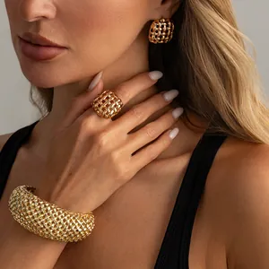 Dettaglio di set vintage bracciale rigido, anello e orecchini in maglia dorata intrecciata.