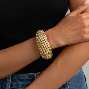 Primo piano di un bracciale rigido vintage in maglia intrecciata dorata sul polso