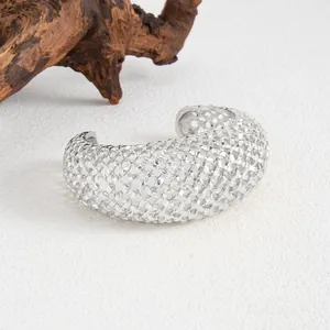Dettaglio macro del bracciale rigido a rete intrecciata in metallo argento retrò.