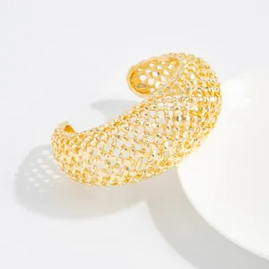 Dettaglio di un bracciale a polsino aperto in maglia intrecciata dorata vintage