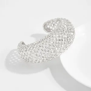 Dettaglio di un bracciale rigido aperto in maglia intrecciata argento in stile retrò.
