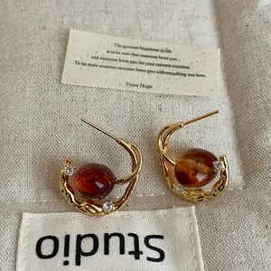 Detailed macro shot of vintage gold-toned hoop earrings with amber oval resin beads.