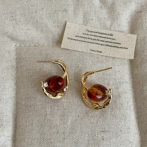 Detail view of vintage amber resin earrings with gold metal frame and small crystal accents