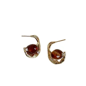 Elegant amber oval resin earrings with gold metal frame and sparkling cubic zirconia accents.