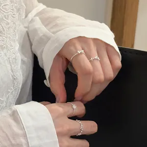 Macro view of delicate bow and flower silver rings worn on hands with lace shirt