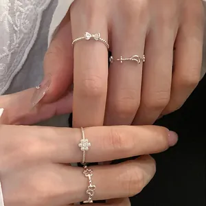 Detailed close-up showing a set of delicate silver bow, moon, and flower rings on fingers