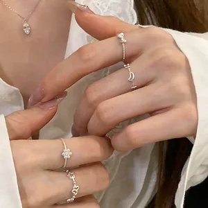 Close-up of minimalist silver rings with bow, moon and flower patterns on hands