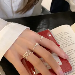 Detailed close-up of delicate silver-tone rings with bow and flower charms on a hand