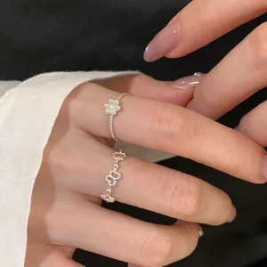 Close-up detail of dainty silver rings featuring delicate pearl flower and butterfly motifs