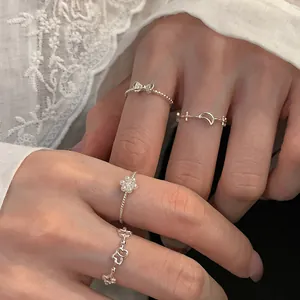 Detailed view of dainty bow and pearl flower rings worn with elegant lace clothing