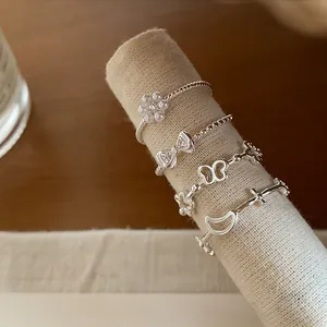 Close-up detail of delicate silver rings featuring bow, butterfly and flower motifs