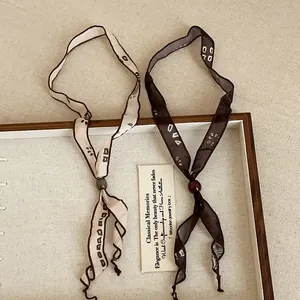 Elegant vintage minimalist printed ribbon scarf necklaces in cream and brown patterns.