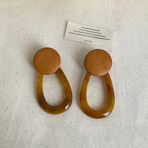 Handmade amber resin earrings featuring geometric oval hoops and natural wooden studs