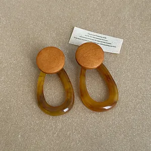 Detailed macro view of amber resin teardrop earrings with round wooden top pieces