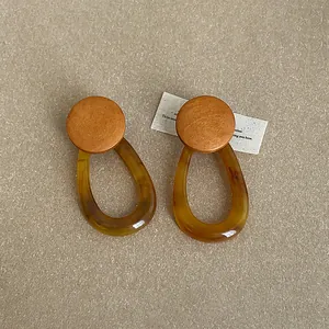 Detailed macro view of amber resin and wooden stud earrings with hollow oval shape