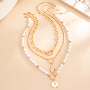 Vue détaillée du collier doré multicouche avec perles baroques et pendentif pièce