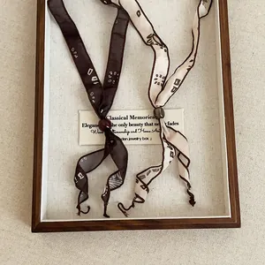 Detail view of minimalist printed ribbon necklaces in vintage brown and beige silk style