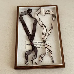 Detailed view of minimalist printed ribbon scarf necklaces in a wooden display box
