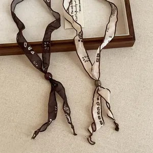 Close-up of minimalist printed silk scarf necklaces with adjustable beads in vintage style.