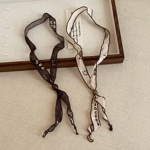 Detail view of retro printed ribbon scarf necklaces in brown and cream