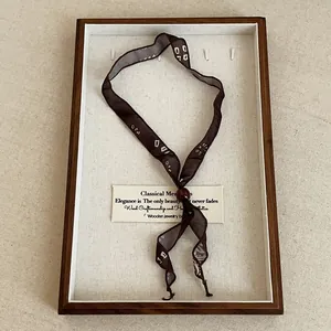 Retro brown printed silk ribbon necklace with a red bead detail in a wooden display.