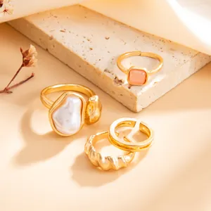 Primer plano macro de anillos de oro chic con perla barroca y detalle de piedra rosa
