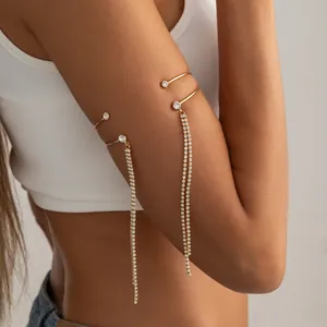 Dettaglio di un bracciale da braccio dorato a doppio strato con lunghe nappe di strass