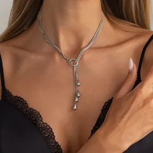 Nahaufnahme einer silbernen Schlangenkette mit Wassertropfen-Anhängern an einem Model.