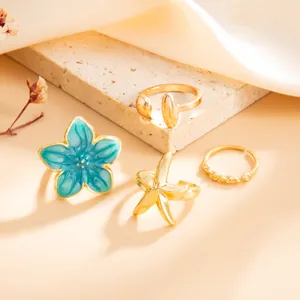 Vista detallada del juego de anillos de flor de esmalte azul y estrella de mar oro