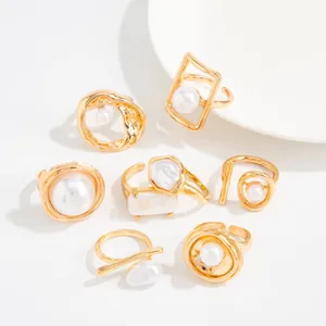 Nahaufnahme von sieben vergoldeten Ringen mit weißen Barockperlen im Vintage-Stil.