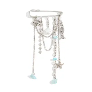 Vue détaillée d'une broche épingle de sûreté argentée avec charms marins et turquoises.