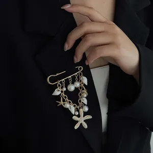 Close-up detail of a gold starfish and pearl charms brooch on a black blazer jacket.