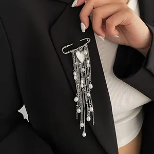 Close-up of a silver safety pin brooch with long pearl chains and heart pendant