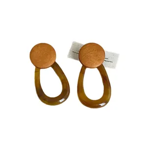 Vintage amber resin teardrop earrings with round wooden studs on white background