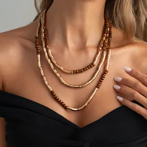 Detailed view of a three-layered necklace with metallic tubes and brown wooden beads.