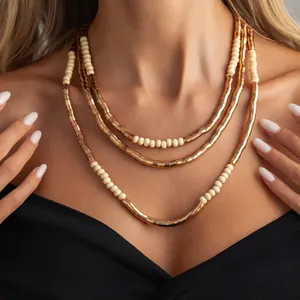 Close-up of layered gold textured metal necklace with cream beads on a model
