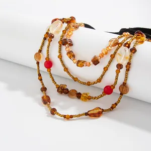 Close-up of Bohemian multi-layer beaded leg chain with amber and red accents on elastic band.