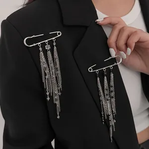 Nahaufnahme einer Punk-Sicherheitsnadel-Brosche mit langen Quastenketten auf dem Blazer.