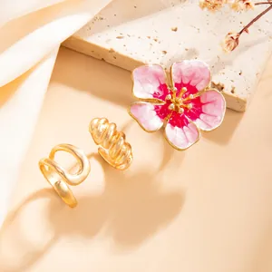 Gedetailleerd overzicht van de roze emaille bloem en gouden spiraal open ringenset dames