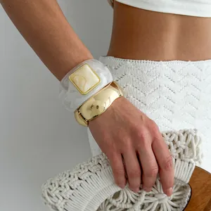 Detailed view of vintage marble resin and chunky gold bangle set on model's wrist
