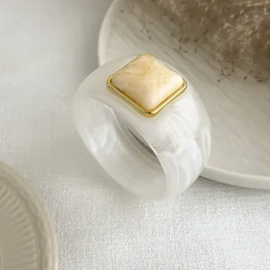 Macro view of retro marbled resin bangle with gold-framed square inlay detail ornament.
