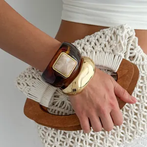 Close-up of vintage resin tortoiseshell and gold wavy chunky bracelets on a model