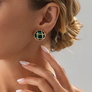 Close-up van vintage goudkleurige mesh oorknopjes met een groene bol van kunsthars