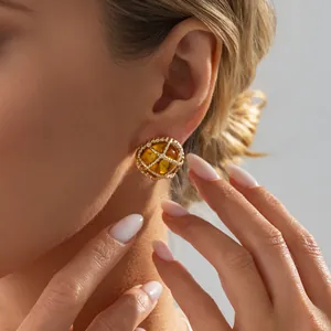 Elegante vintage gouden oorknopjes met amberhars detail gedragen door een vrouwelijk model