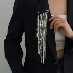 Elegant oversized safety pin brooch with long pearl and chain tassels on a blazer